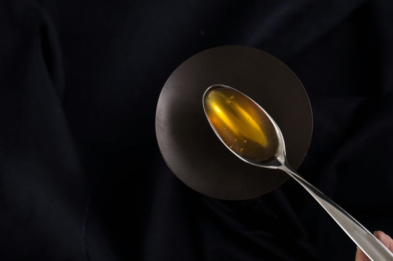 Cuchara con aceite de oliva virgen extra sobre fondo oscuro