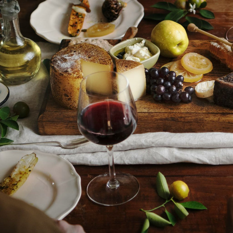 Mesa con vino tinto, pan, queso y aceite de oliva arbequina en un maridaje gourmet
